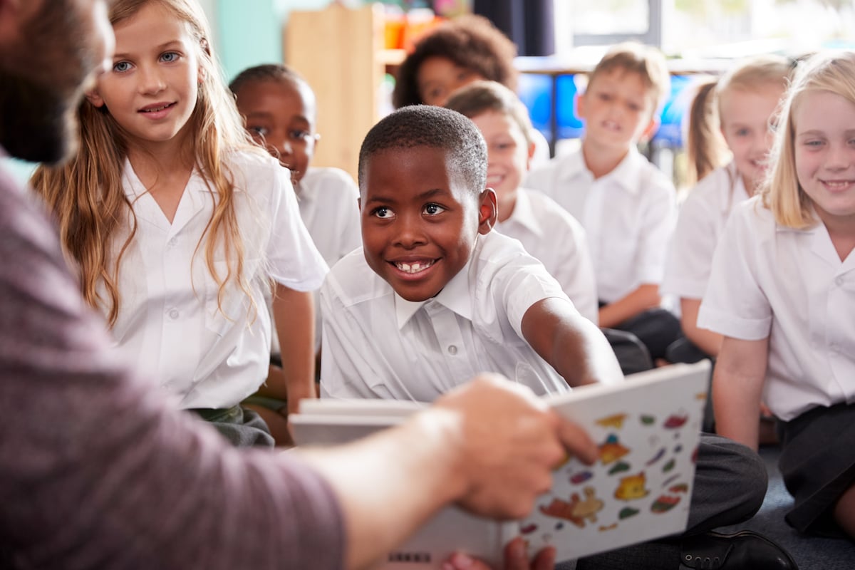 male teacher reading to a group of elementary student