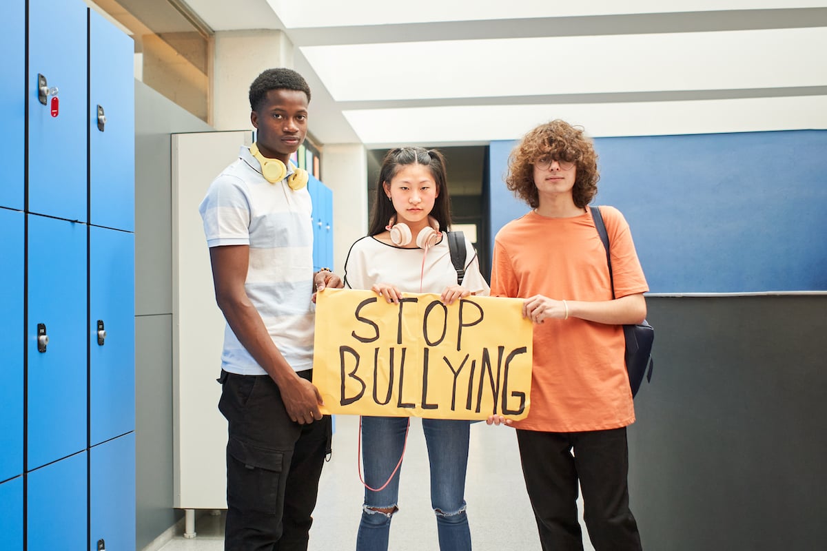 group of students holding a banner that reads stop bullying