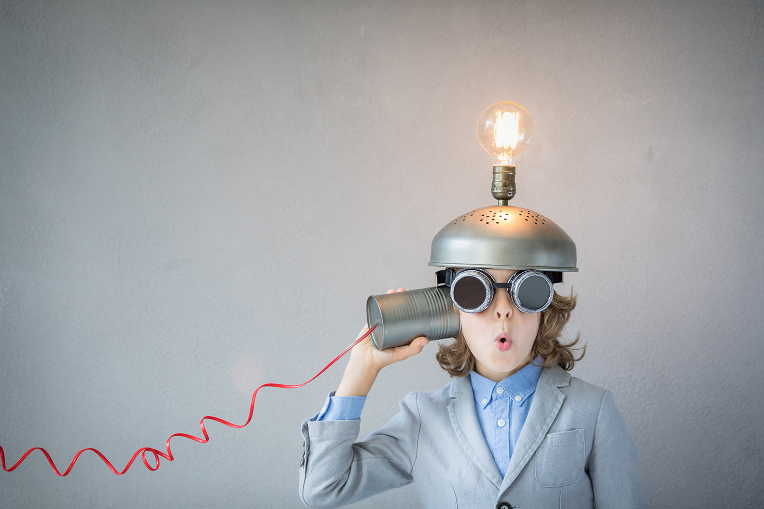 boy listening to a tin can with a light bulb on his head