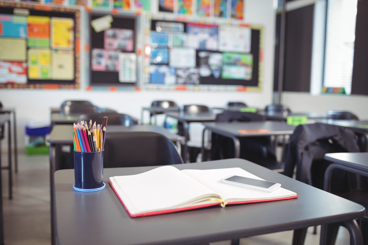 mobile phone on open book on a desk in an empty classroom