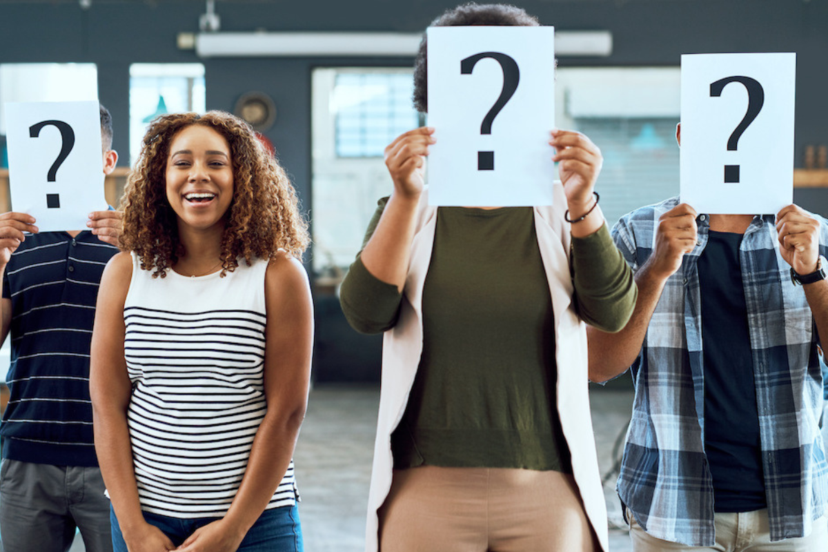 people lined up holding question marks