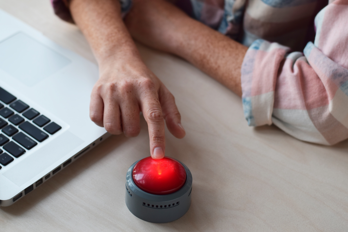 woman sitting at desk and pressing red panic button