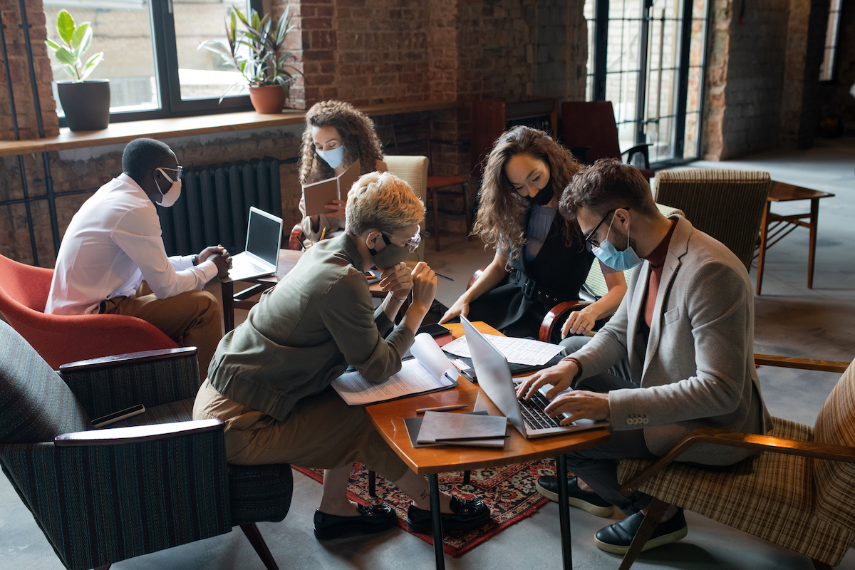 business people in masks working around tables