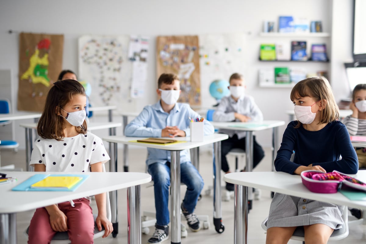 children with masks sitting in class