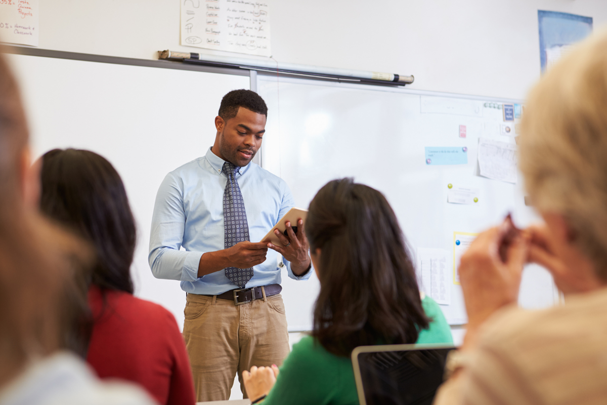 male-teacher-looking-at-tablet